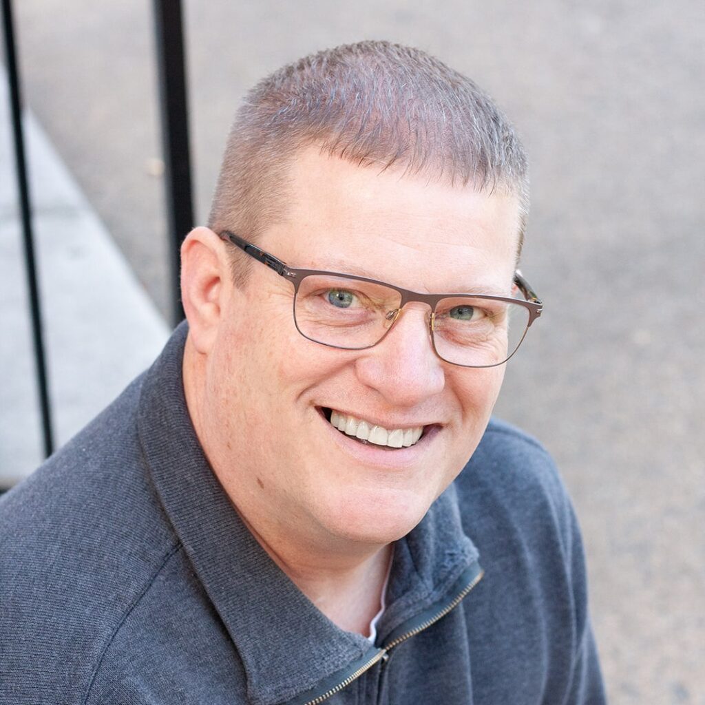 A man with glasses smiling for the camera.